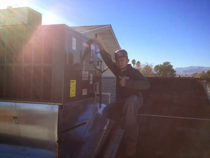 HVAC technician performing AC Tune-Up on a rooftop unit in Sugar Land
